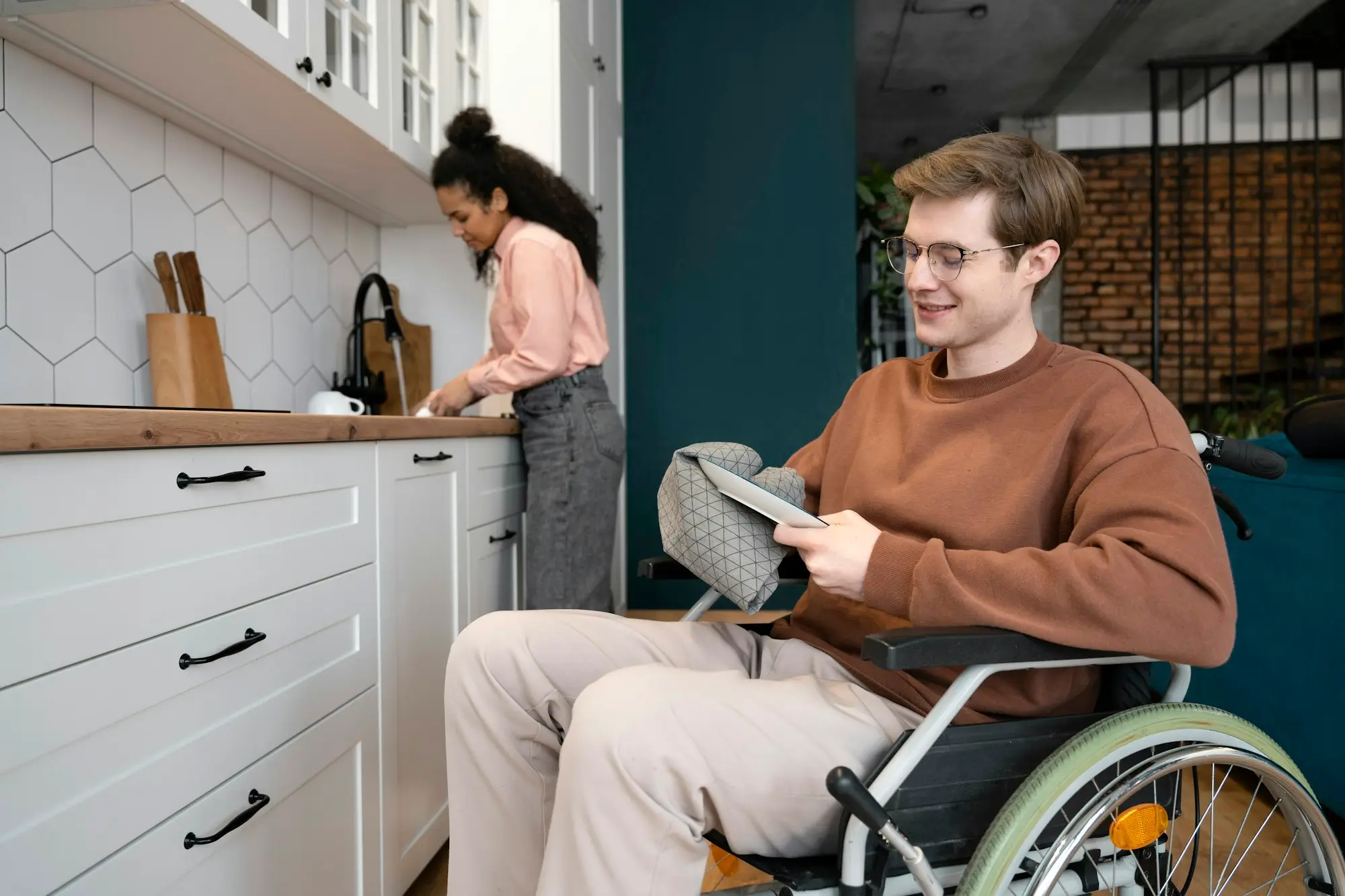 Wheelchair user at home with a support worker in the kitchen